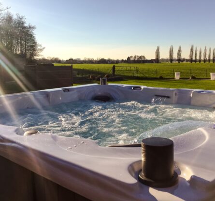 Jacuzzi spa buiten met wat erin dat aan het bubbelen is. Buiten is er een mooi uitzicht op land