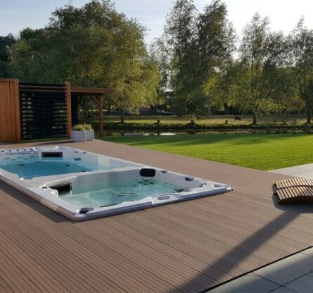 Een ingebouwde jacuzzi spa op een houten vlonder buiten op een zonnige dag