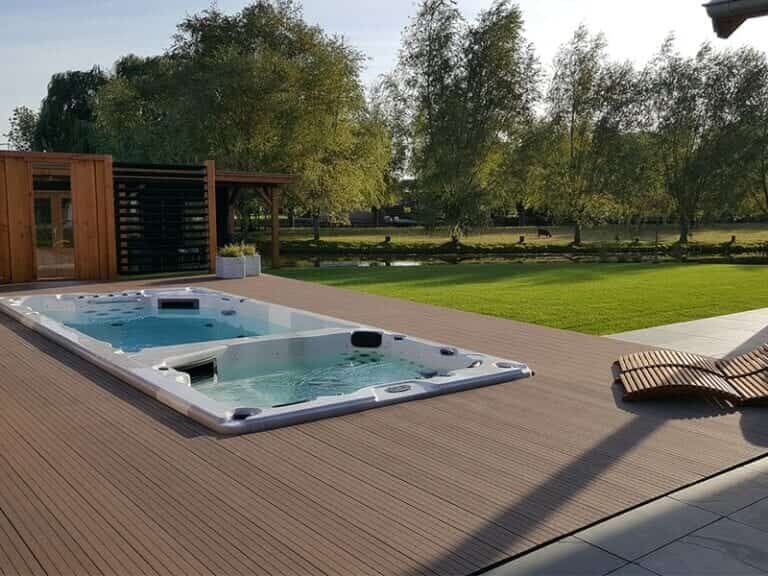 Een ingebouwde jacuzzi spa op een houten vlonder buiten op een zonnige dag