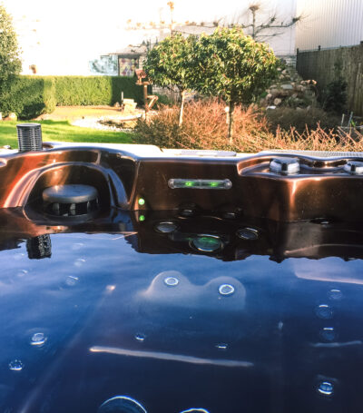 jacuzzi met bruine binnenkant, gevuld met water en uitzicht op een tuin