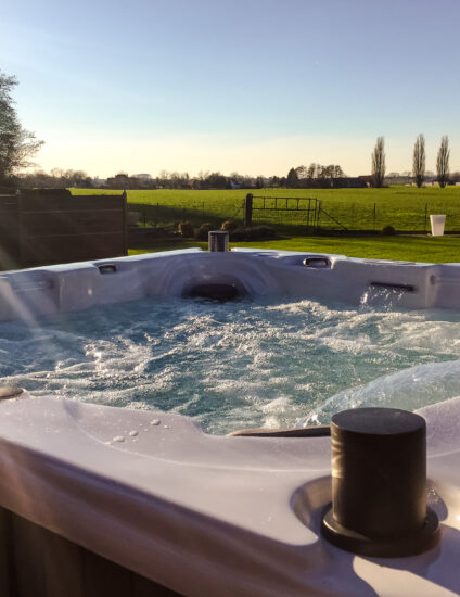 Jacuzzi spa buiten met wat erin dat aan het bubbelen is. Buiten is er een mooi uitzicht op land