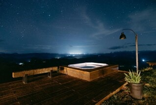 half ingebouwde jacuzzi met hout eromheen tijdens de avond