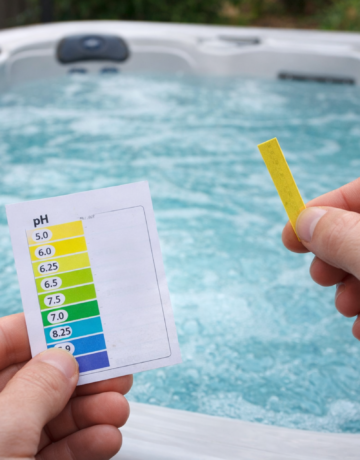een hand met een test om de pH waarde van een jacuzzi te meten, deze is te laag