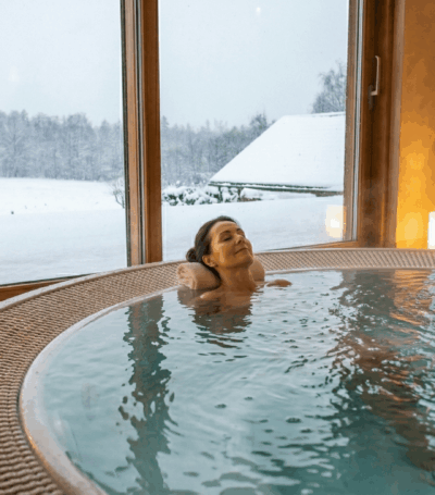 Vrouw diep aan het ontspannen in een jacuzzi in de winter met sneeuw in de achtergrond
