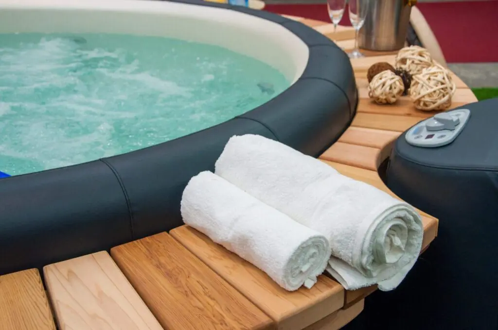 Een ingezoomde foto op een mooie jacuzzi hot tob met een decoratie van handdoeken, champagne en een mooi interieur om de spa