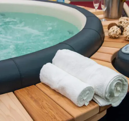 Een ingezoomde foto op een mooie jacuzzi hot tob met een decoratie van handdoeken, champagne en een mooi interieur om de spa