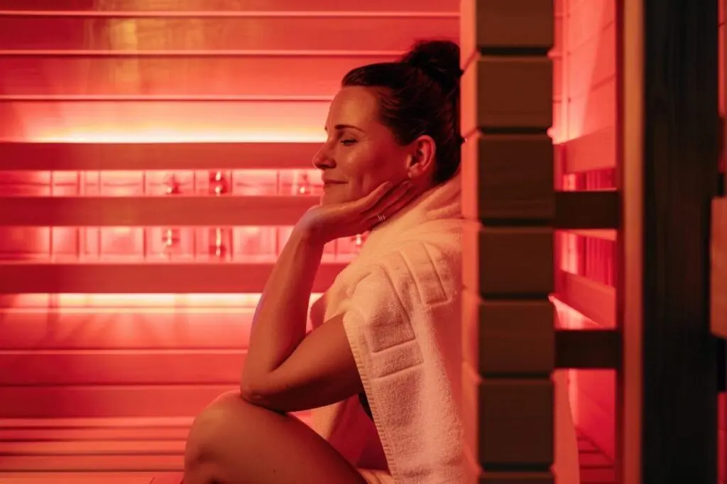Een vrouw die geniet in een Infrarood sauna. De IR cabine is rood verlicht