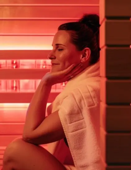 Een vrouw die geniet in een Infrarood sauna. De IR cabine is rood verlicht