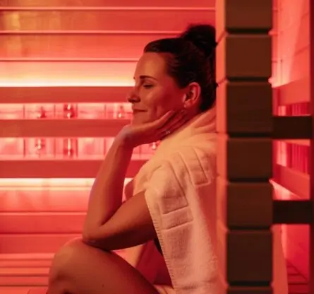 Een vrouw die geniet in een Infrarood sauna. De IR cabine is rood verlicht