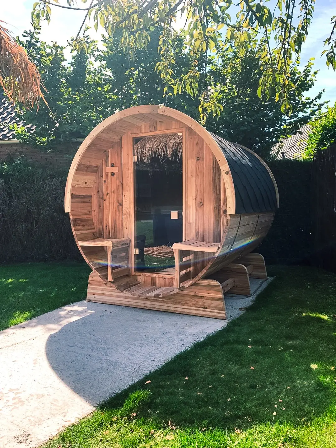 Barrelsauna in de buitenlucht met zon en groene natuur op de achtergrond