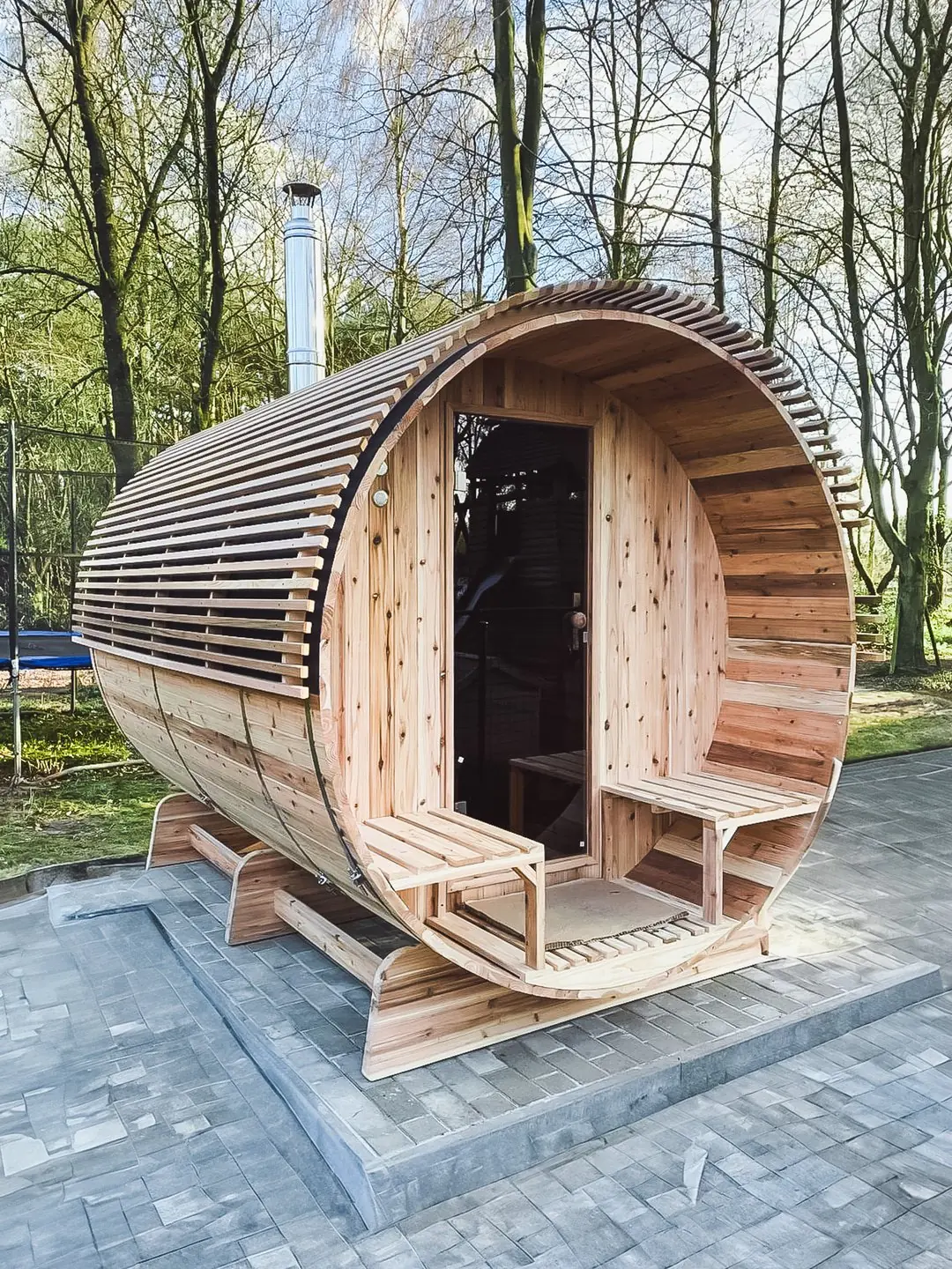 Barrel sauna op een stenen ondergrond met groene natuur op de achtergrond