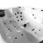 Binnenaanzicht van een witte spa met meerdere zitplaatsen, ergonomische vormen en diverse massagejets op verschillende hoogtes.