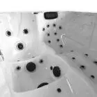 Binnenaanzicht van een witte spa met meerdere zitplaatsen, ergonomische vormen en diverse massagejets op verschillende hoogtes.