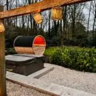 Barrelsauna in een herfstlandschap met warm rood sfeerlicht aan de binnenzijde