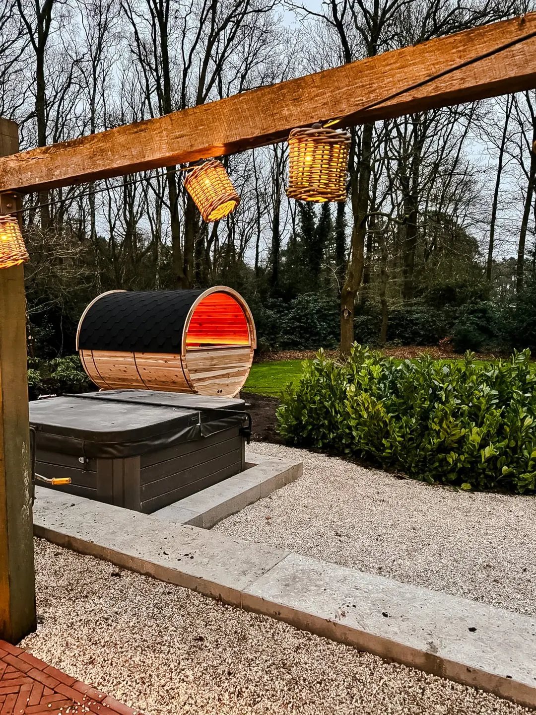 Barrelsauna in een herfstlandschap met warm rood sfeerlicht aan de binnenzijde
