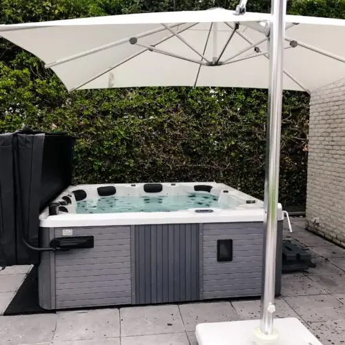 "Jacuzzi met een donkergrijs omhulsel geplaatst onder een witte parasol