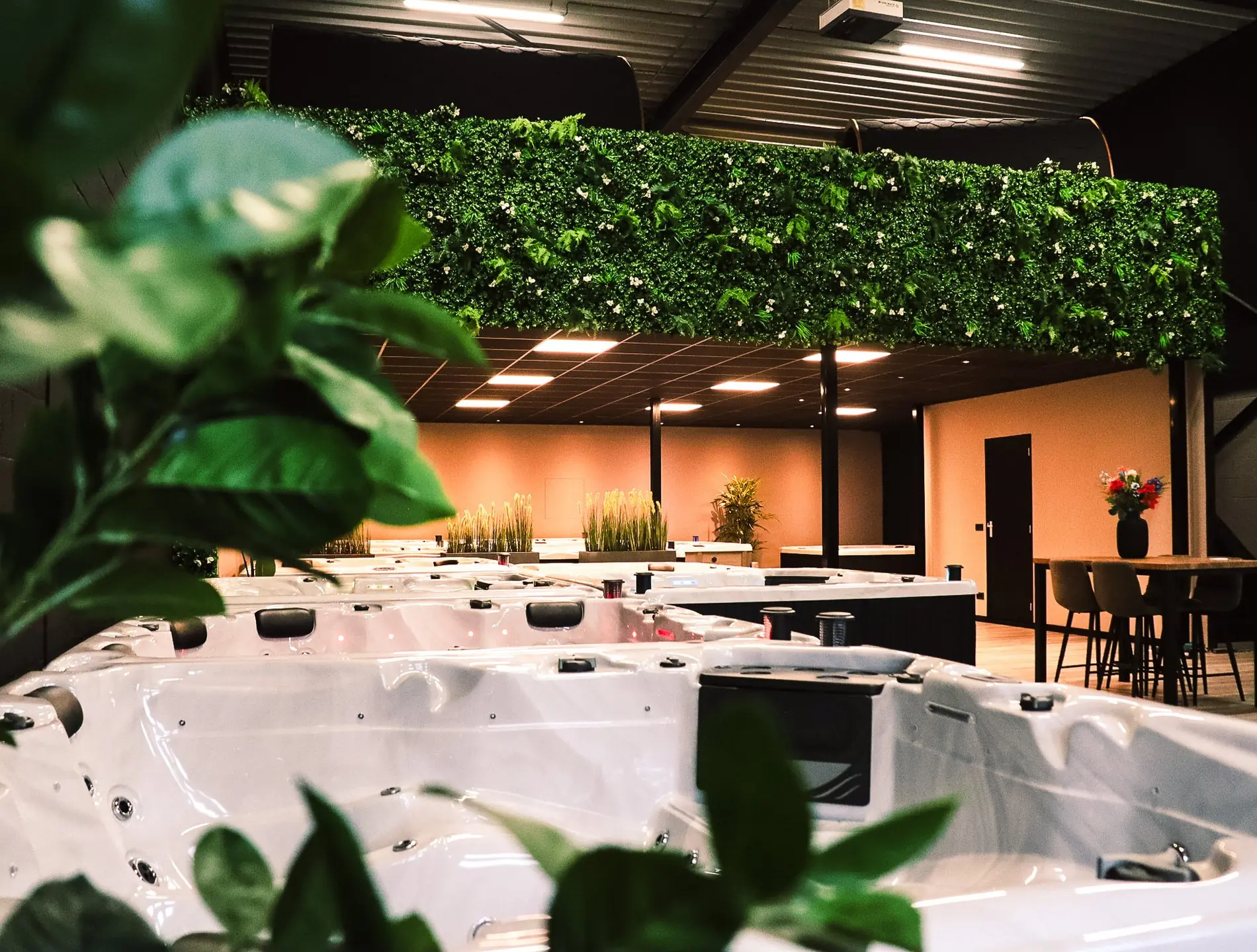 Showroom van Wellnesshuis Benelux met meerdere jacuzzi’s, groene planten en zitgedeelte