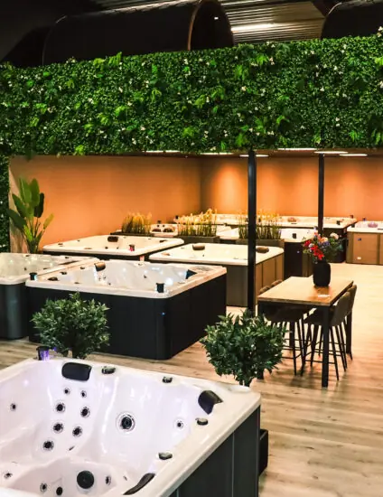 Showroom in Berlicum met negen jacuzzi’s overzichtelijk opgesteld in de ruimte. De ruimte is voorzien van een laminaat vloer en een kunsthaag ter decoratie.
