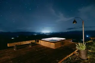 half ingebouwde jacuzzi met hout eromheen tijdens de avond